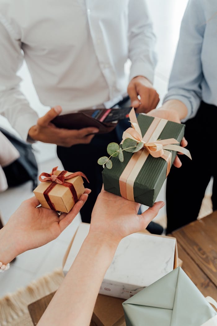 People exchanging beautifully wrapped gift boxes in a close-up view, showcasing a warm gesture.