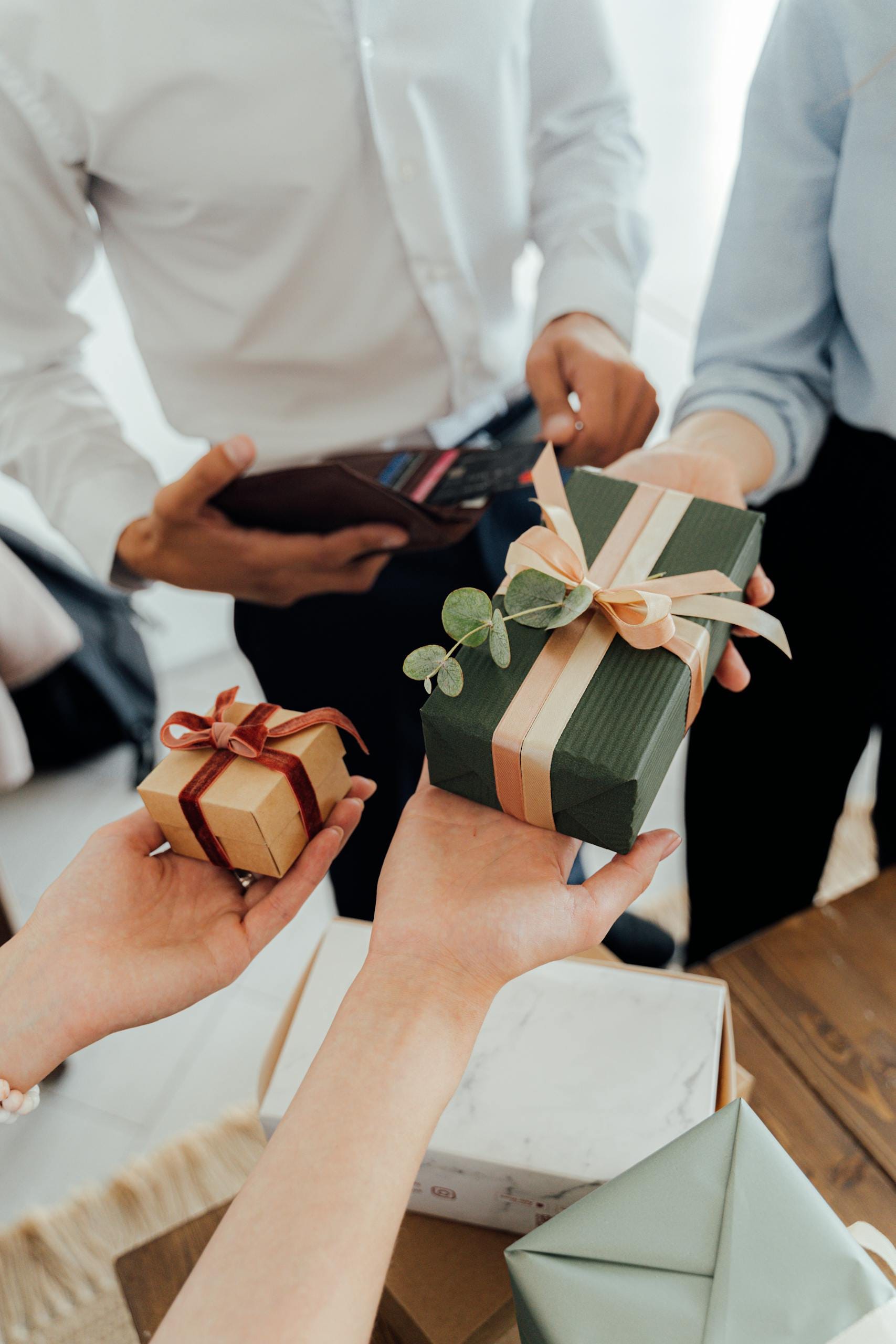 People exchanging beautifully wrapped gift boxes in a close-up view, showcasing a warm gesture.