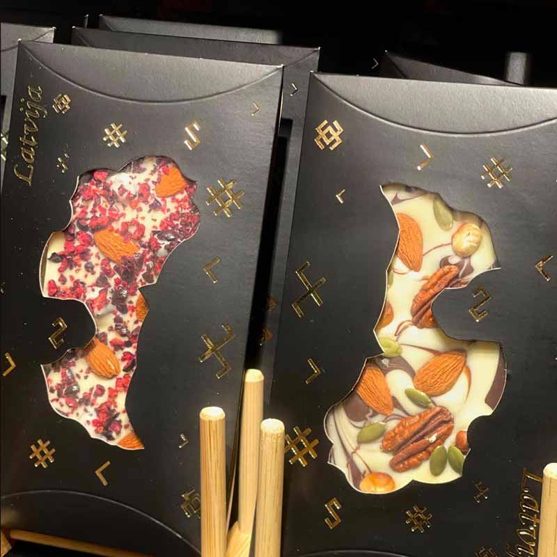 Gifts and souvenirs from baltic states Premium handcrafted Latvian chocolate bars with artistic fruit and nut designs in elegant black gift boxes