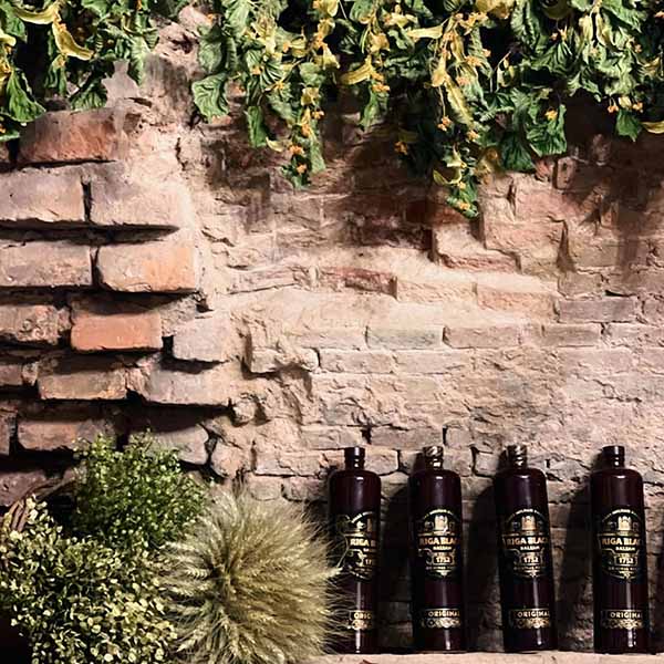 Gifts and souvenirs from baltic states Riga Black Balsam bottles displayed against rustic stone walls and natural Latvian herbs