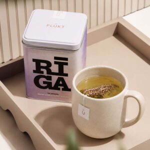 : Riga Original tea tin next to a cup of brewed herbal flower tea