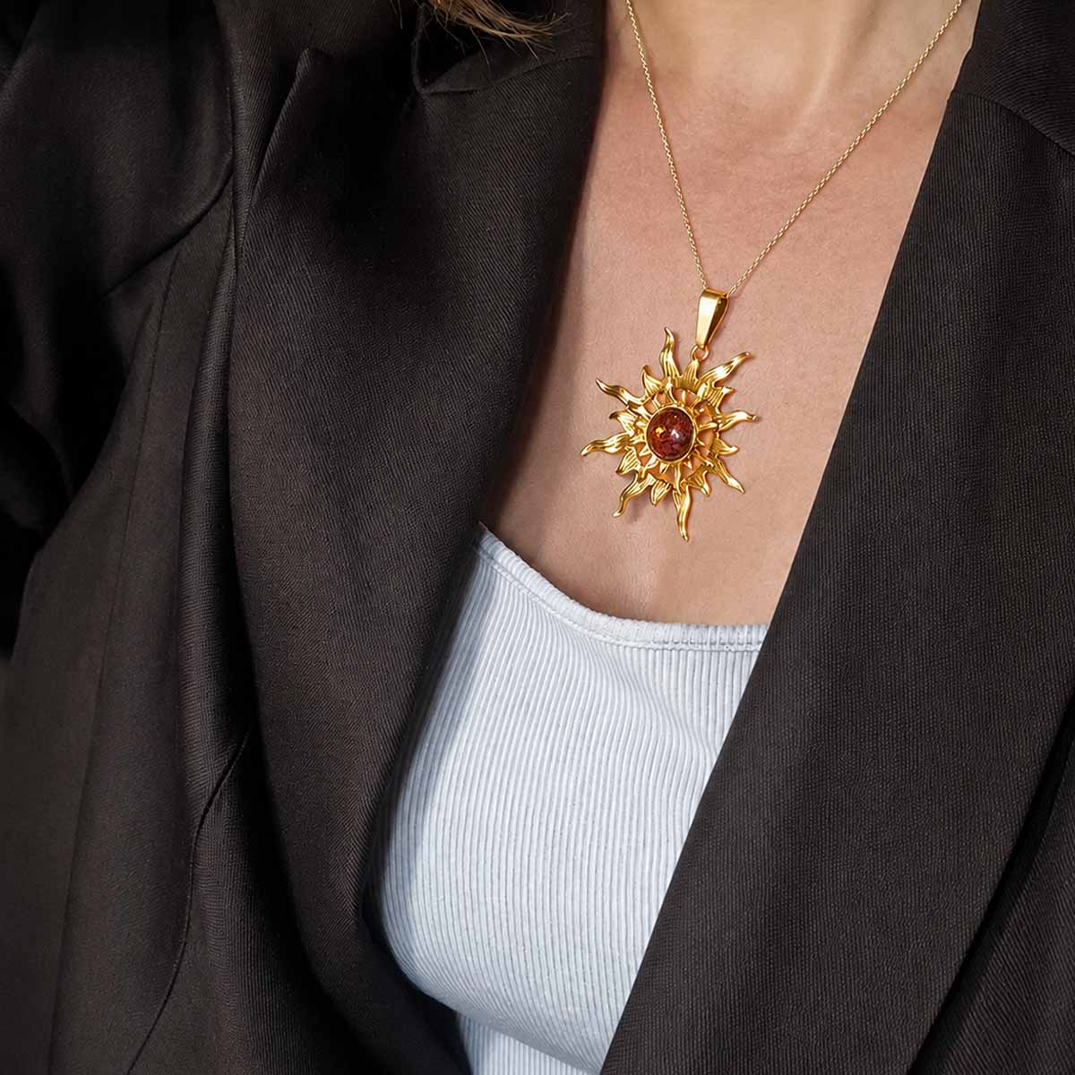Silver pendant in sun shape with orange amber piece, gold-plated